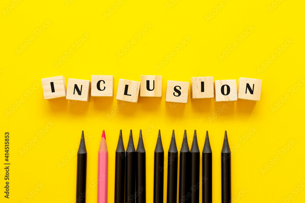Inclusion concept word on wooden cubes and pencils on yellow background Inclusion concept word on wooden cubes and pencils on yellow background