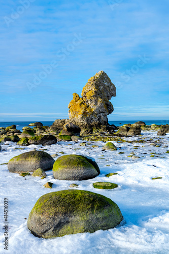 Cold winter day with ice on the water with a limestone stack and ocean in the background on the island of Gotland in Sweden