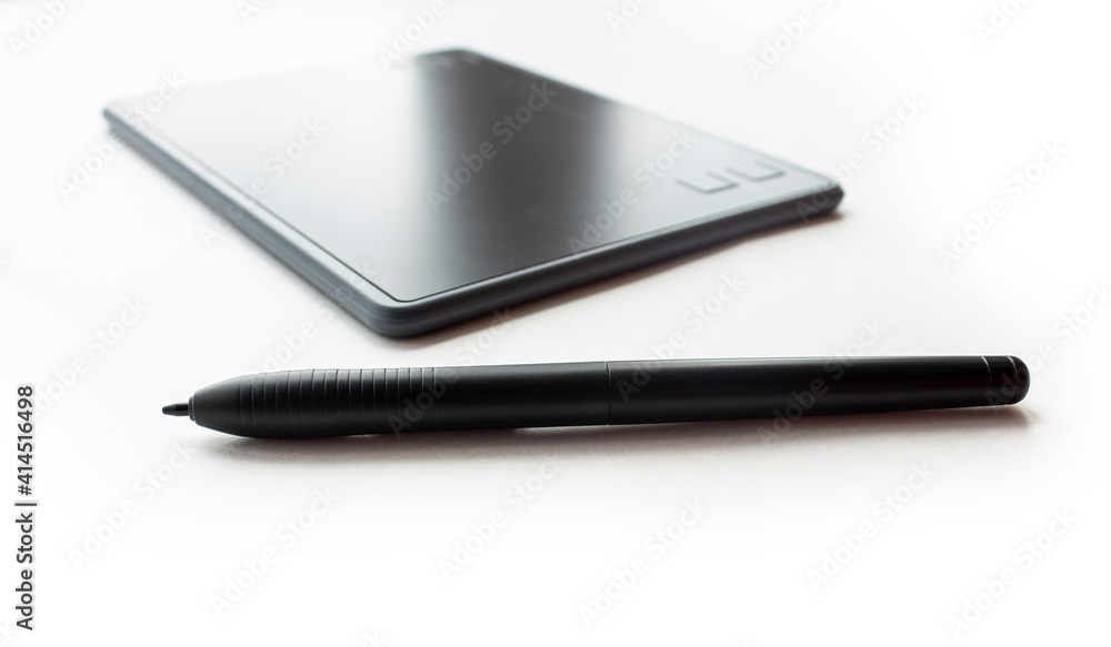 Black graphic design tablet with control buttons on a white background. Graphic tablet with a touch pen for working on a computer and laptop Black graphic design tablet with control buttons on a white background. Graphic tablet with a touch pen for working on a computer and laptop