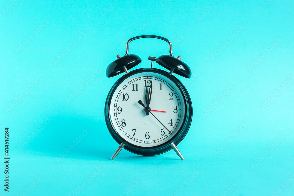 Classic alarm clock indicates 12 o'clock isolated blue background Classic alarm clock indicates 12 o'clock isolated blue background