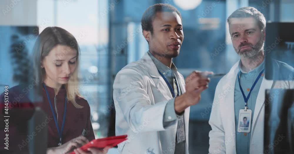 Multi-ethnic trip of medical people discussing x-ray pictures and disease symptoms in modern healthcare office private clinic hospotal. Multi-ethnic trip of medical people discussing x-ray pictures and disease symptoms in modern healthcare office private clinic hospotal.