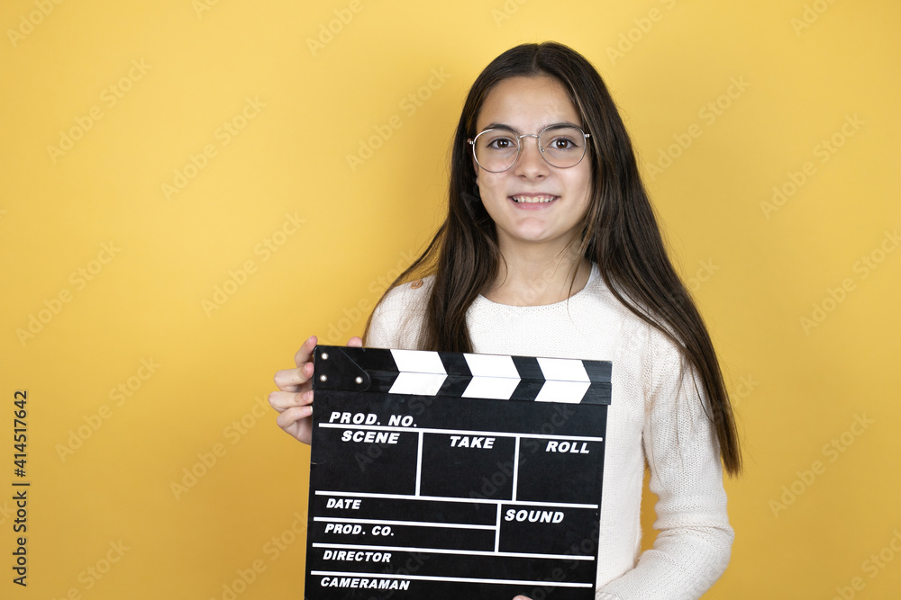Beautiful child girl wearing casual clothes holding clapperboard very happy having fun
