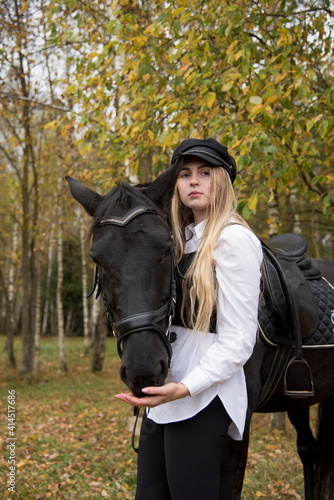 Portrait of a teenage girl , hugging a Chestnut horse against the background of an autumn forest. © FO_DE