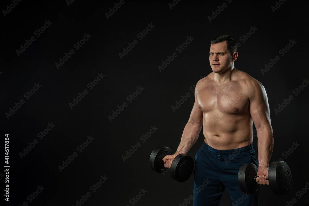Man strains muscles with dumbbells pumps bicep bare torso Young male style model, modern confidence Beautiful Fashion cool background black bodybuilder