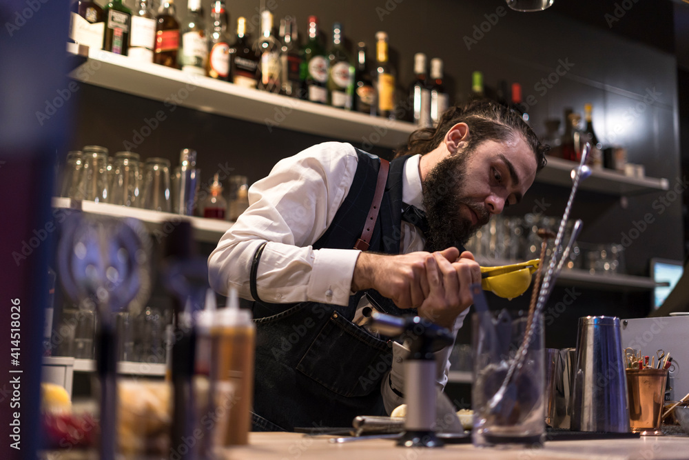 Expert barman is making cocktail at night club. Expert barman is making cocktail at night club.