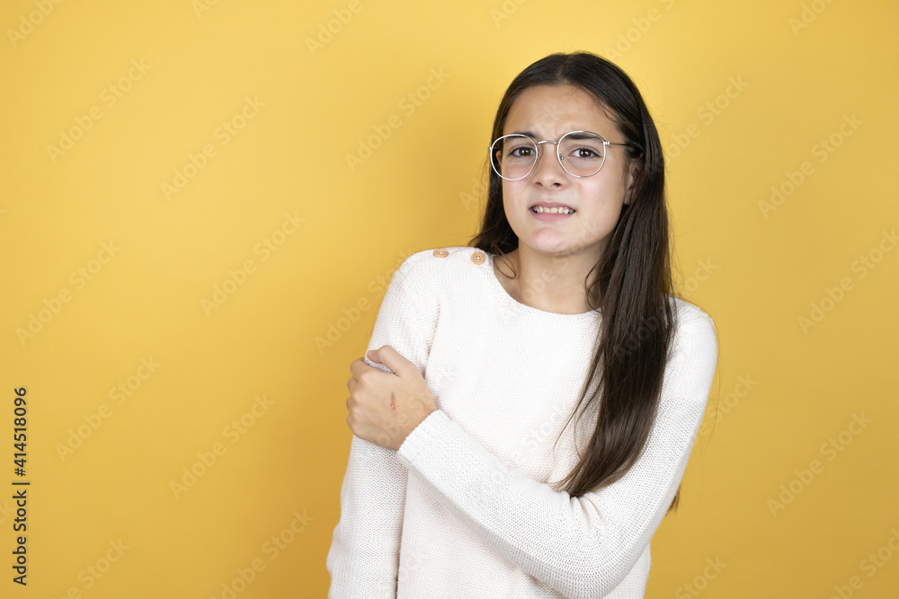 Beautiful child girl wearing casual clothes with pain on her shoulder and a painful expression Beautiful child girl wearing casual clothes with pain on her shoulder and a painful expression