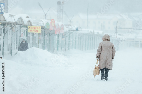 a man with difficulty walks through deep snow, snowdrifts on the sidewalk after a heavy snowfall. poor operation of public utilities in winter © evgavrilov