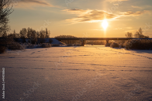 The sun shines across the bridge over the frozen river on a sunny morning, noone on a bridge