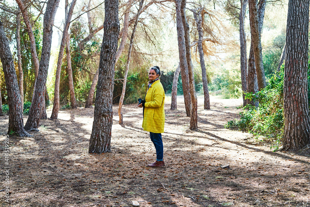 Woman looks to take photos with analog reflex camera in forest Woman looks to take photos with analog reflex camera in forest