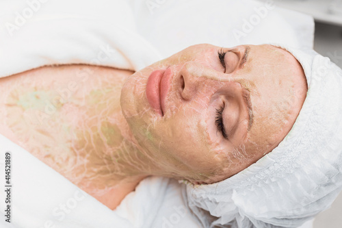 Dried enzyme mask on the face and neck of a woman. Rejuvenation and facelift in a cosmetology clinic