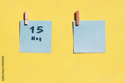 May 15st . Day of 15 month, calendar date. Two blue sheets for writing on a yellow background. Top view, copy space. Spring month, day of the year concept photo