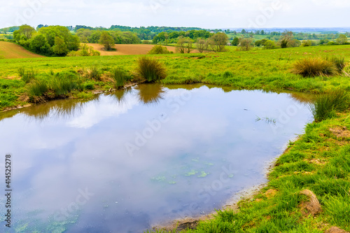 A view across a dew pond towards the village of Gumley near Market Harborough, UK in springtime