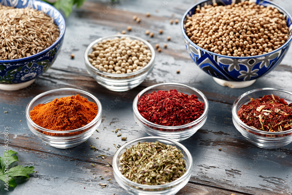 Various spices in bowls on grey table. Paprika, turmeric, red pepper, cumin, coriander. Powdered spices