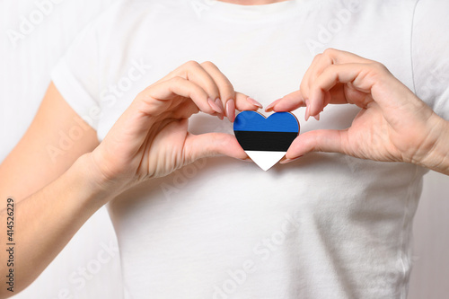 Love Estonia. The girl holds a heart in the form of the flag of Estonia on her chest. Estonian concept of patriotism photo