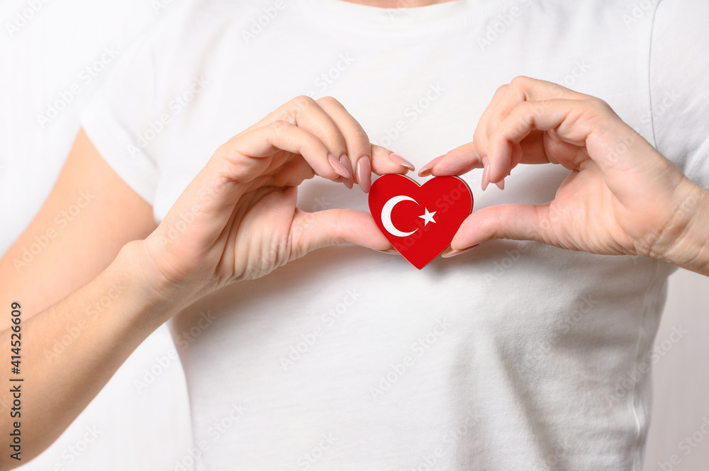 Love Turkey. The girl holds a heart in the form of the flag of Turkey on her chest. Turkish patriotism concept Love Turkey. The girl holds a heart in the form of the flag of Turkey on her chest. Turkish patriotism concept
