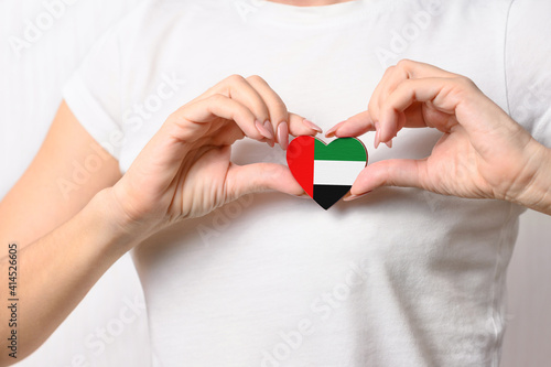 Love United Arab Emirates (UAE). The girl holds a heart in the form of the flag of UAE on her chest. Concept of patriotism UAE