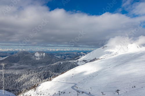 Snow-covered mountains and ski slopes with clouds on background. Ski resort Roza Khutor. Sochi. Russia.