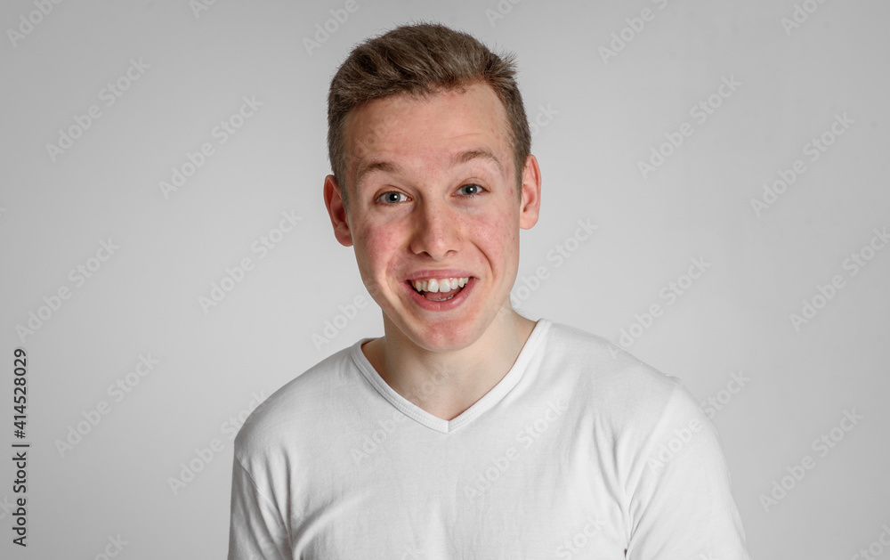 teen guy looking into the frame happy surprised can't believe raised eyebrows
and smiling with teeth on a white background in a white T-shirt teen guy looking into the frame happy surprised can't believe raised eyebrows
and smiling with teeth on a white background in a white T-shirt