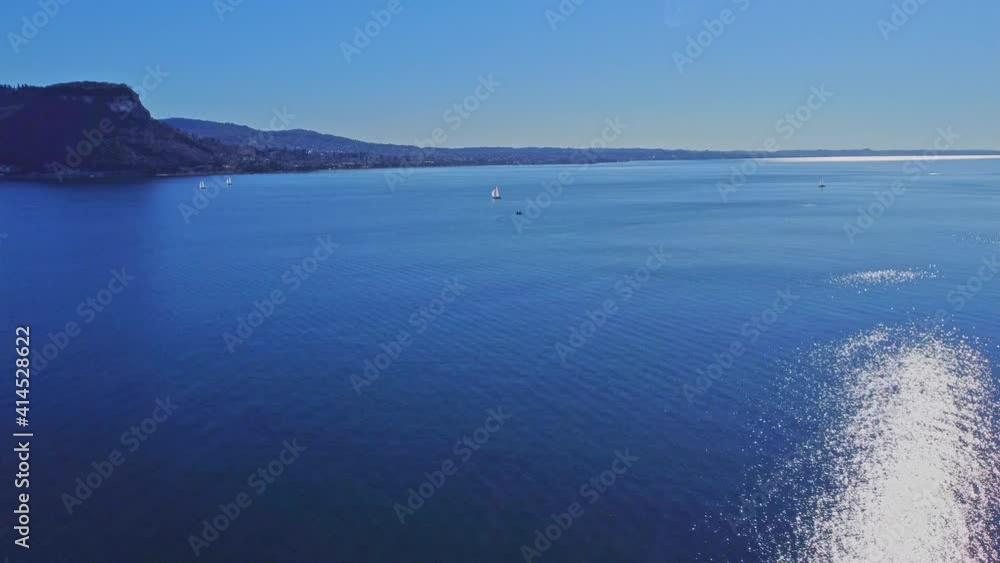 Pleasant aerial view of the coast of Lake Garda. Lonely Sailboat in the middle of the lake on a Sunny day. Pleasant aerial view of the coast of Lake Garda. Lonely Sailboat in the middle of the lake on a Sunny day.