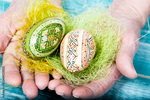Painted wooden eggs in the hand of senior woman. Closeup