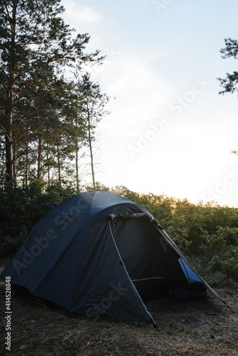 green tourist tent on the background of the forest at sunset