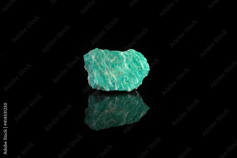 Natural rock amazonite mineral stone from Kola Peninsula on black glass background.