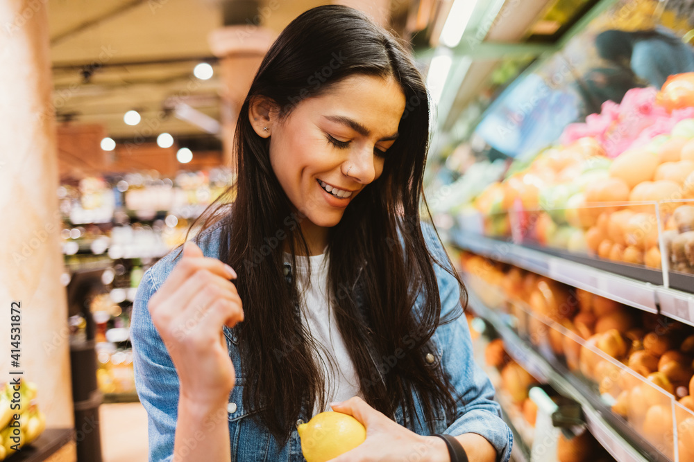 Portrait happy young beautiful woman shopper standing in supermarket