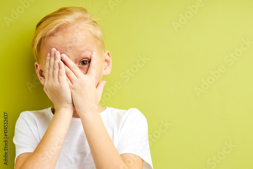 Fotografie scared kid boy covering eyes and mouth with hands, frightened and shocked by something, hiding emotions