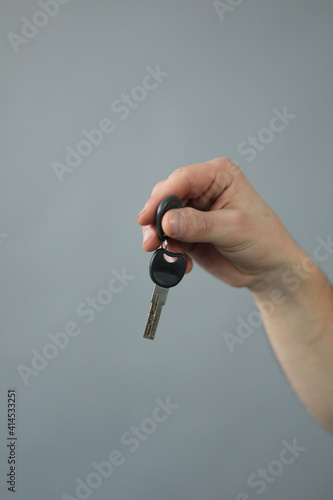 Hand with key in front of wall