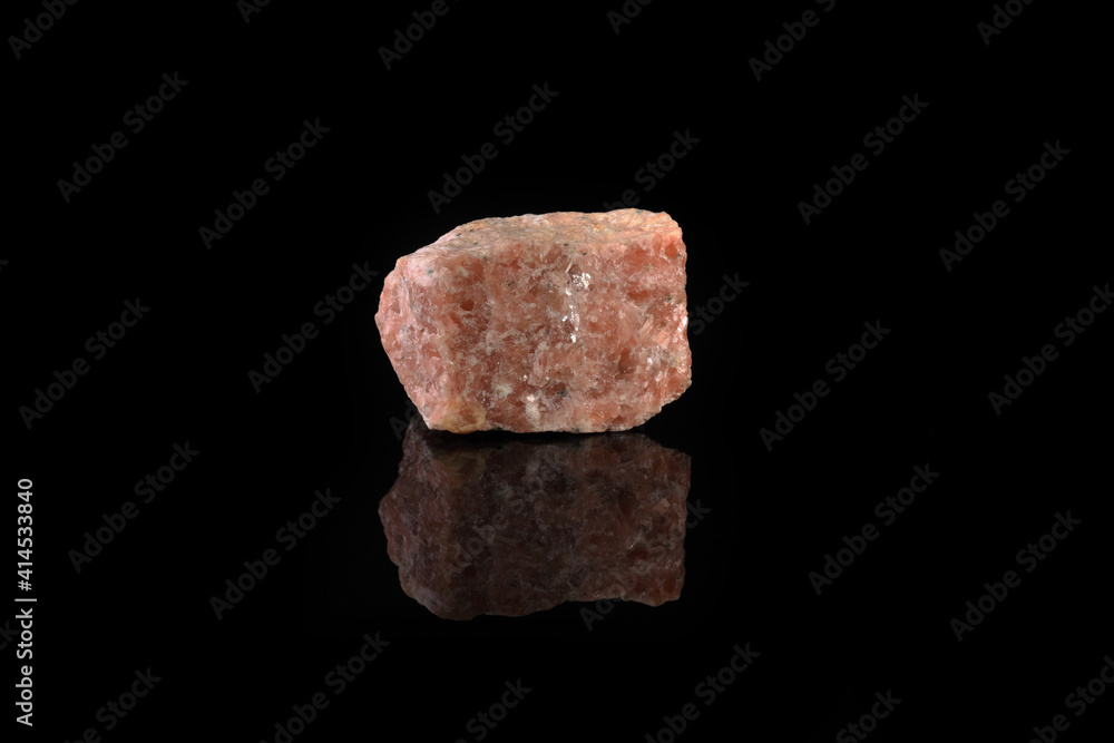 Natural mineral rock specimen - pink marble from Slyudyanka, Baikal, Russia on black glass background.