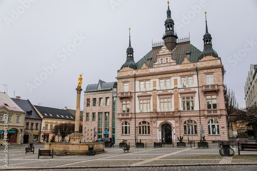 Neo-renaissance house of Ceska sporitelna and Fountain with golden Marian statue, baroque historical buildings, Square of Bohemian Paradise in winter day, Turnov, Czech Republic