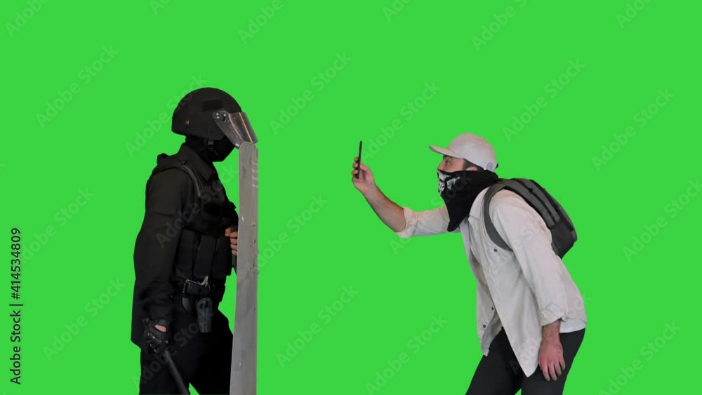 Aggressive protester shooting riot police on smartphone on a Green Screen, Chroma Key. Aggressive protester shooting riot police on smartphone on a Green Screen, Chroma Key.