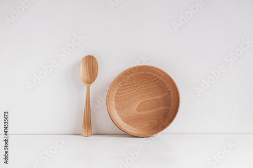 Empty wooden bowl and wooden spoon on a white table background. Copy, empty space for text