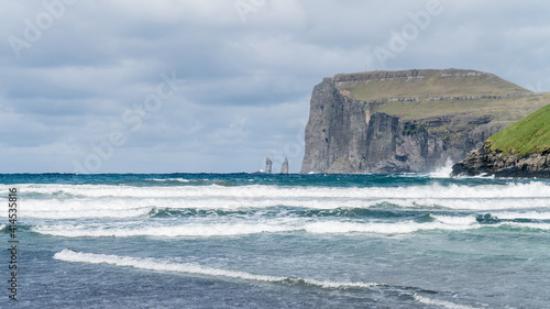 Risin and Kellingin rocks as seen from Tjornuvik bay with waves hitting the shore on Streymoy on the Faroe Islands, Denmark, Europe photo