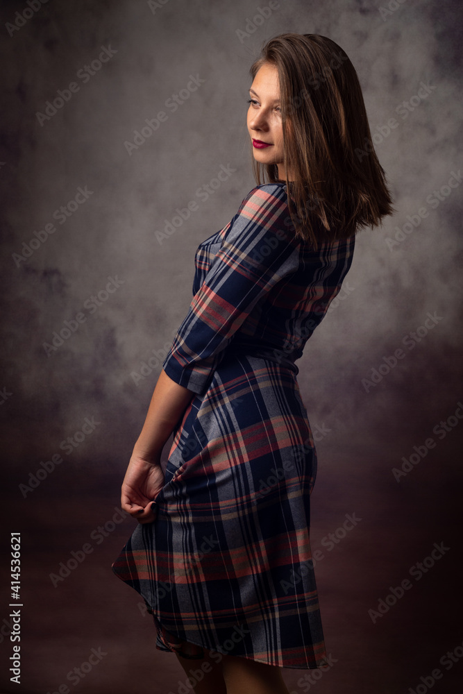Portrait of a beautiful girl in a checkered dress, the girl is turned sideways Portrait of a beautiful girl in a checkered dress, the girl is turned sideways