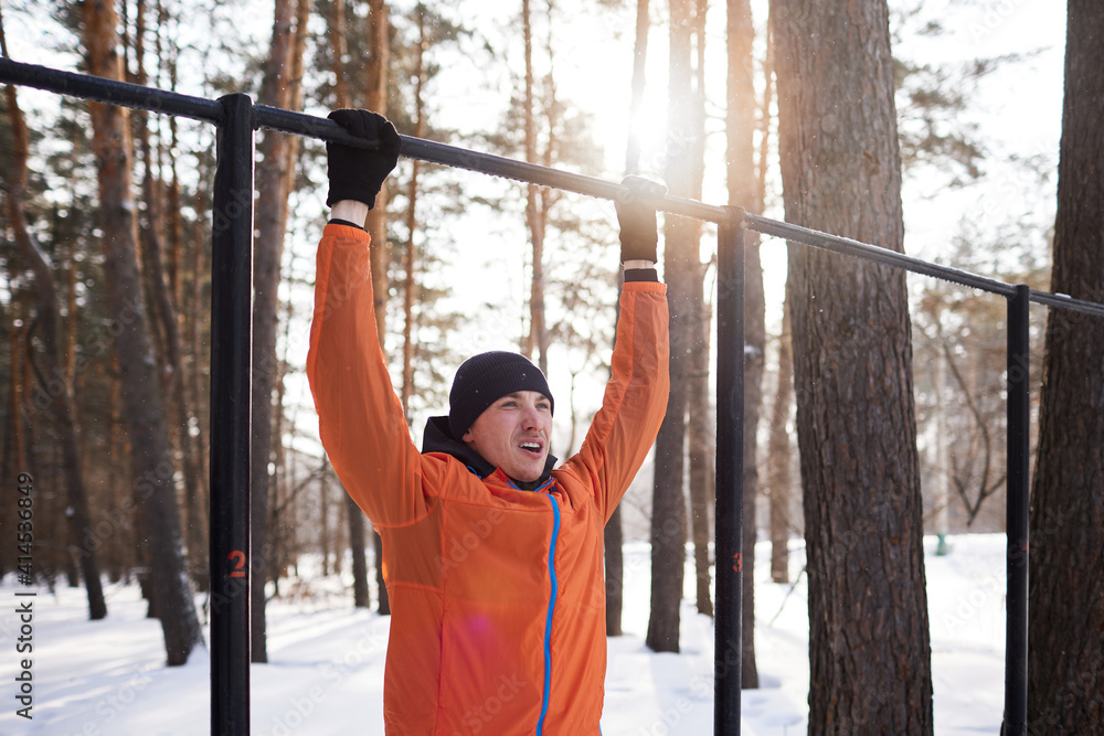 Fototapeta premium A young man is engaged in a workout on a sports field on a winter day