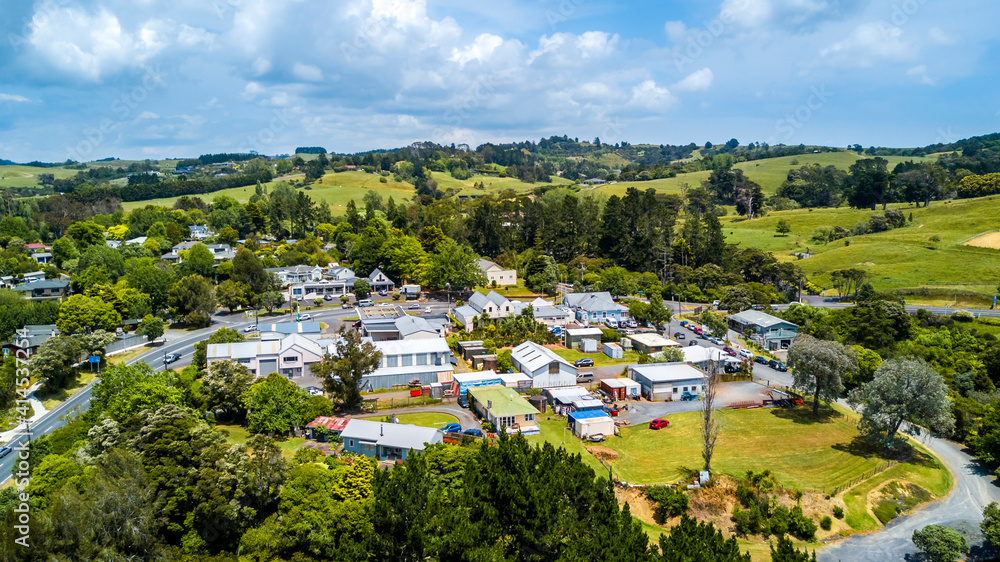 Aerial view of a little village in the middle of the countryside spotted with farms and forest. Auckland, New Zealand.