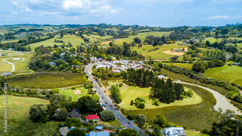 Aerial view of a little village in the middle of the countryside spotted with farms and forest. Auckland, New Zealand.