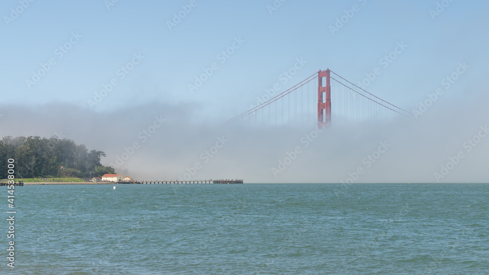 San Francisco, USA - August 2019: Golden Gate Bridge under fog, with one tower visible. The Golden Gate Bridge is a suspension bridge spanning the Golden Gate.