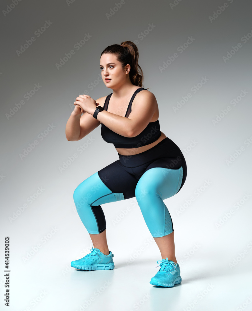 Photo of posing athletic female. Smiling woman with fit, curvy body doing  sport exercises. Model having slim, stunning figure, wearing sport trousers  and top, also sneackers for professional run. Stock-bilde