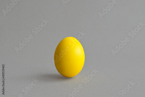 A yellow egg painted on a gray background. Happy Easter. Copy of the space. Minimalism.