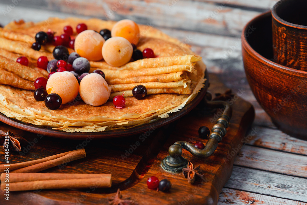 Fototapeta premium Golden pancakes with frozen fruits, decor and honey in a rustic style
