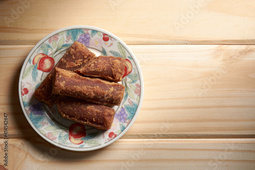 A top view of panela slices on a small plate on wooden table. Also known as rapadura, it is unrefined whole cane sugar typical of Central and Latin America. photo