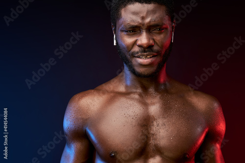 african sportsman in studio, male go in for sport wearing headphones, he looks at camera
