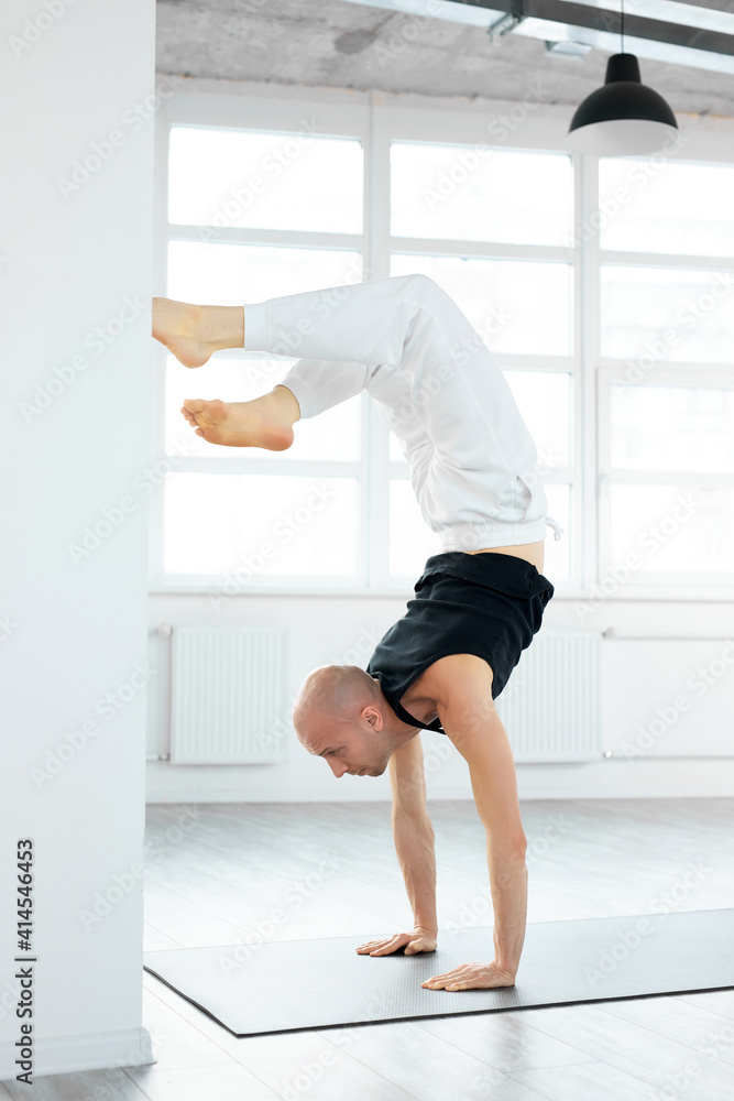 professional yogi man doing scorpion yoga pose in bright studio room. Caucasian male practicing yoga. Yogi concept. Side view. professional yogi man doing scorpion yoga pose in bright studio room. Caucasian male practicing yoga. Yogi concept. Side view.