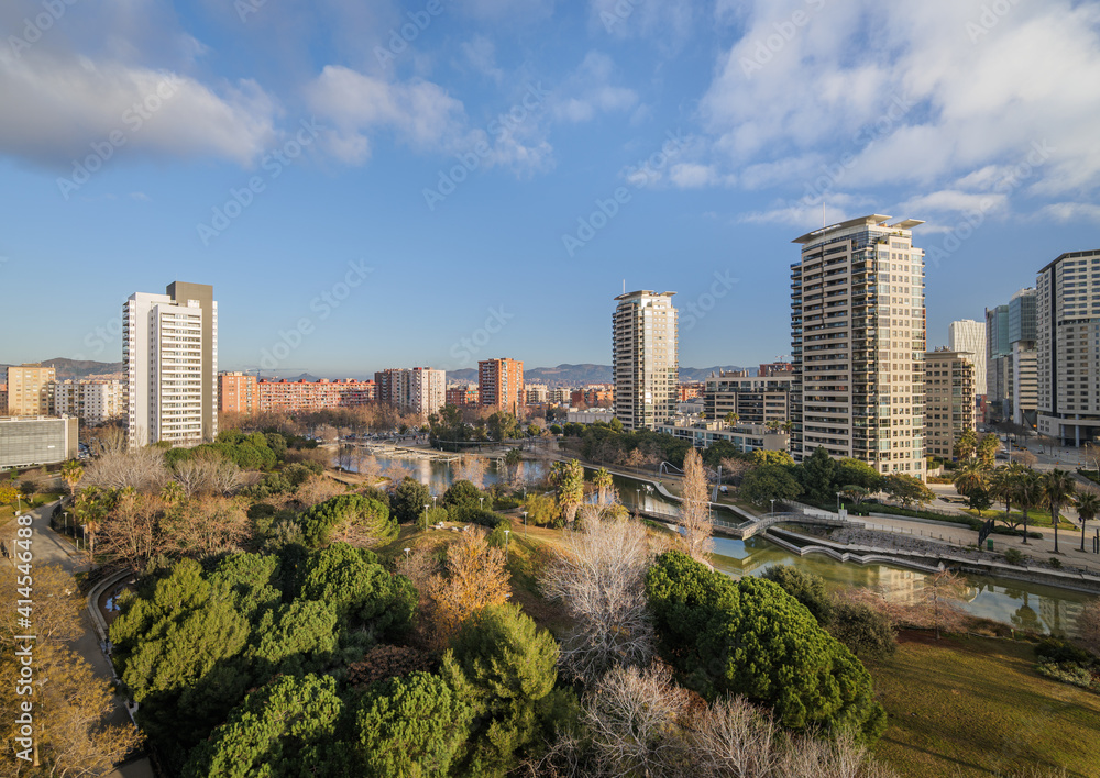 View of expensive area with park and modern high-rise buildings. Diagonal Mar district close to the sea in Barcelona, Spain. Sunny day with clouds.