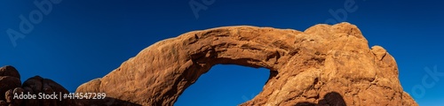 Red sandstone arch against blue sky at sunny day in arches national park in Utah, America