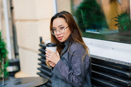 Charming asian woman with beautiful smile reading good news on mobile during rest in coffee shop