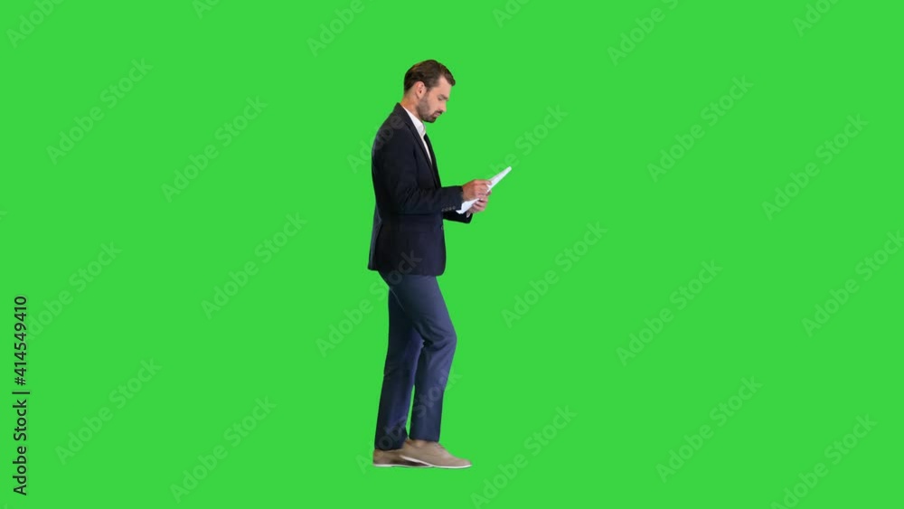 Serious Young Businessman reading documents while walking on a Green Screen, Chroma Key. Serious Young Businessman reading documents while walking on a Green Screen, Chroma Key.