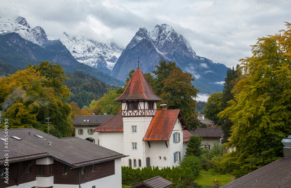 Garmisch, southern Bavaria, Germany. Church, homes and alps mountains with flowers, view from balcony.